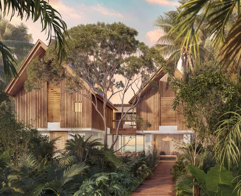 A wooden residence with expansive windows set amid tropical greenery and trees, beneath a pink and blue evening sky.