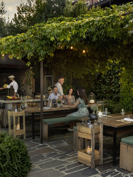 يستمتع الضيوف بمحادثات هادئة على طاولات في الهواء الطلق، محاطة بالعناصر الطبيعية التي تعكس التزام العلامة التجارية بالصحة والاستدامة.