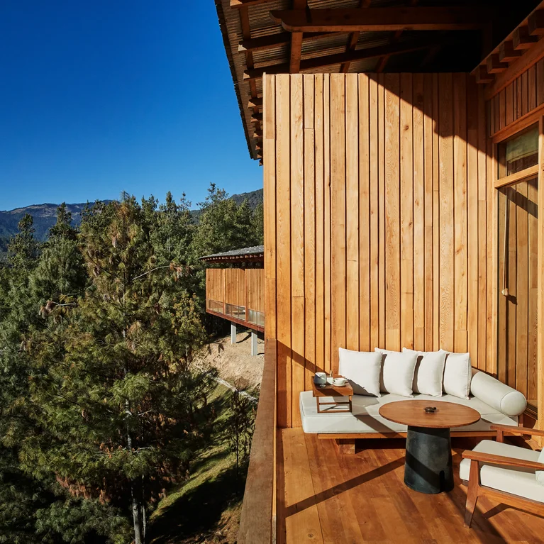 木质阳台配有软垫座椅和桌子,面朝湛蓝天空下的绿树和群山。阳台上设有无障碍座椅,让您坐得更舒适。.