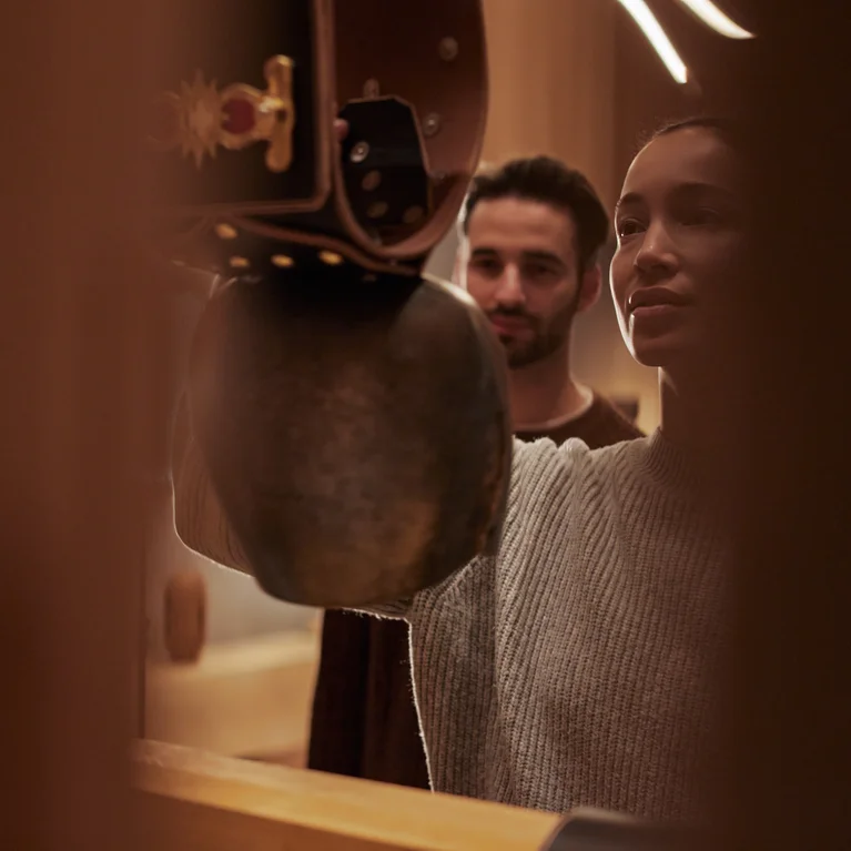 穏やかなインテリアの中で、2人が大きな吊り鐘の中に入ると、柔らかな照明が心地よさとつながりを優先した落ち着いた雰囲気を作り出す。.