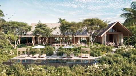 Villa amid abundant greenery, with poolside loungers, umbrellas, and an infinity pool. Blue sky overhead dotted with clouds and birds in flight.