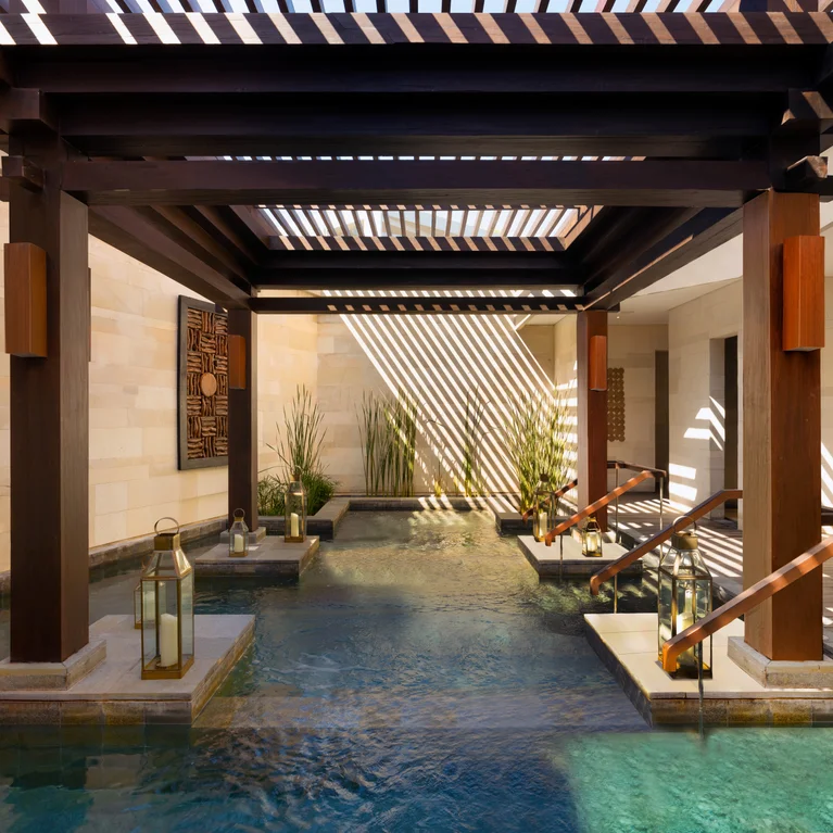 室内泳池设有木制凉棚、自然灯笼照明、绿化和无障碍台阶。阳光透过光束,在水面上形成图案光。.