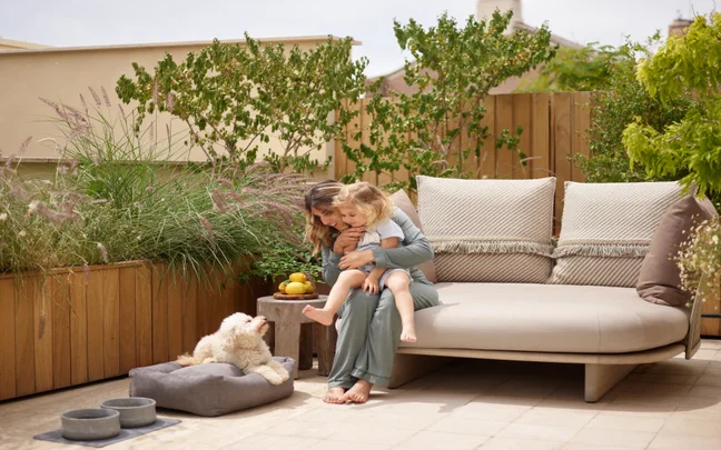 Child seated in a high chair indoors, enjoying an ice cream cone with an expressive, joyful smile. Calm surroundings and natural light create a peaceful scene.