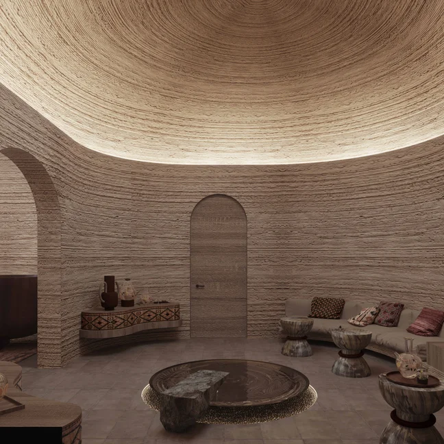 Circular space features textured walls, an arched doorway, curved sofa, small tables and cushions in a serene, nature-inspired setting with gentle lighting.