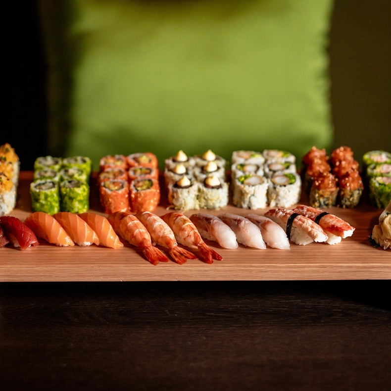 Assorted nigiri and sushi rolls are arranged in orderly rows on a platter, served on a subtly dark background for an elegant dining presentation.