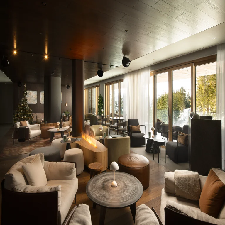 Sitting area featuring a natural-tone sofa, organic wood coffee table, pendant light, and a dark accent wall with an array of white circular décor for sensory balance.