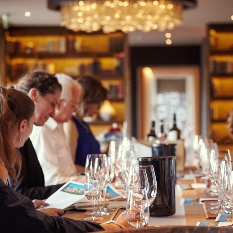 Guests gather at the table with wine glasses, menus and bottles under warm lighting in an inviting and carefully designed dining area.