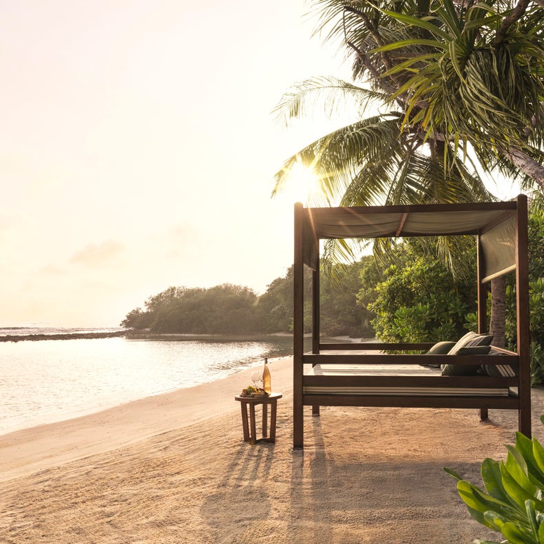 A thoughtfully placed bed overlooks the shoreline, inviting restful sleep close to nature with gentle waves and soft sand enhancing a sense of wellbeing.