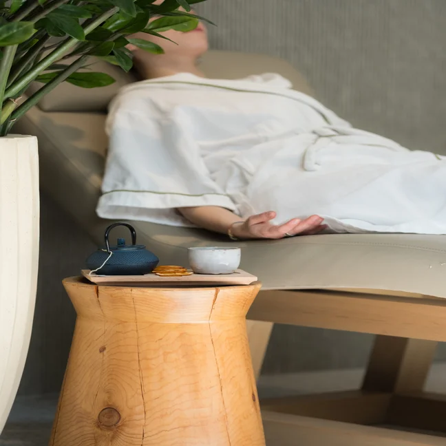 Guest relaxing on a comfortable sofa in a serene setting, reflecting Six Senses’ commitment to wellbeing and mindful spaces.