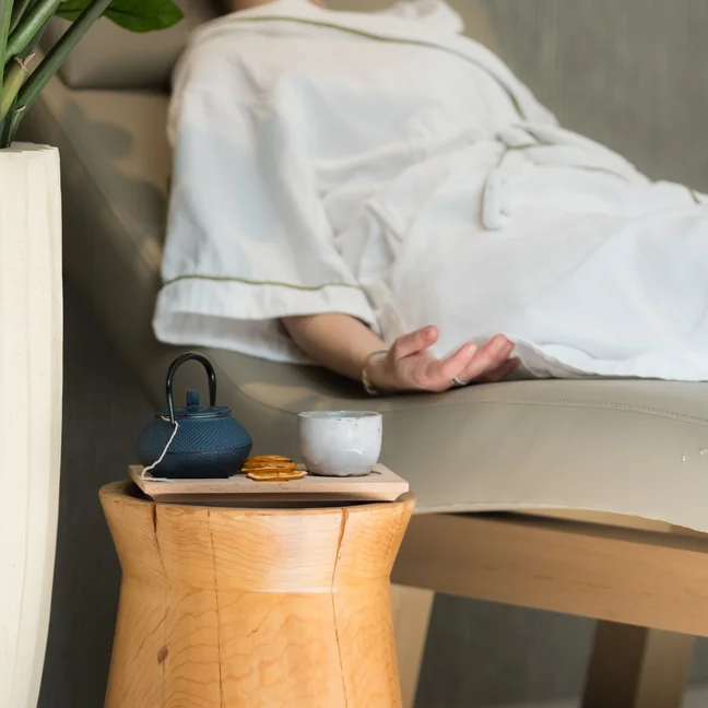 Guest relaxing on a comfortable sofa in a serene setting, reflecting Six Senses’ commitment to wellbeing and mindful spaces.