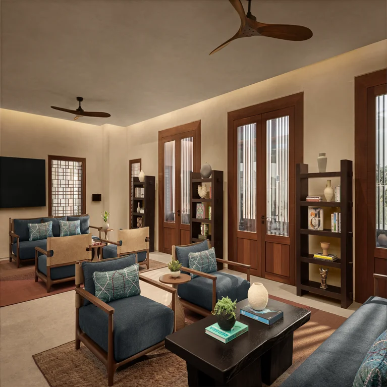 Living room featuring blue armchairs, warm wood shelves, glass doors for natural light, ceiling fans, a TV, and leafy plants on dark tables.