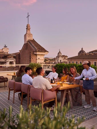 夕暮れ時に屋上レストランで食事をするゲストは、緑とヨーロッパの歴史的建築物の眺めが静かな環境をさらに引き立てる。.