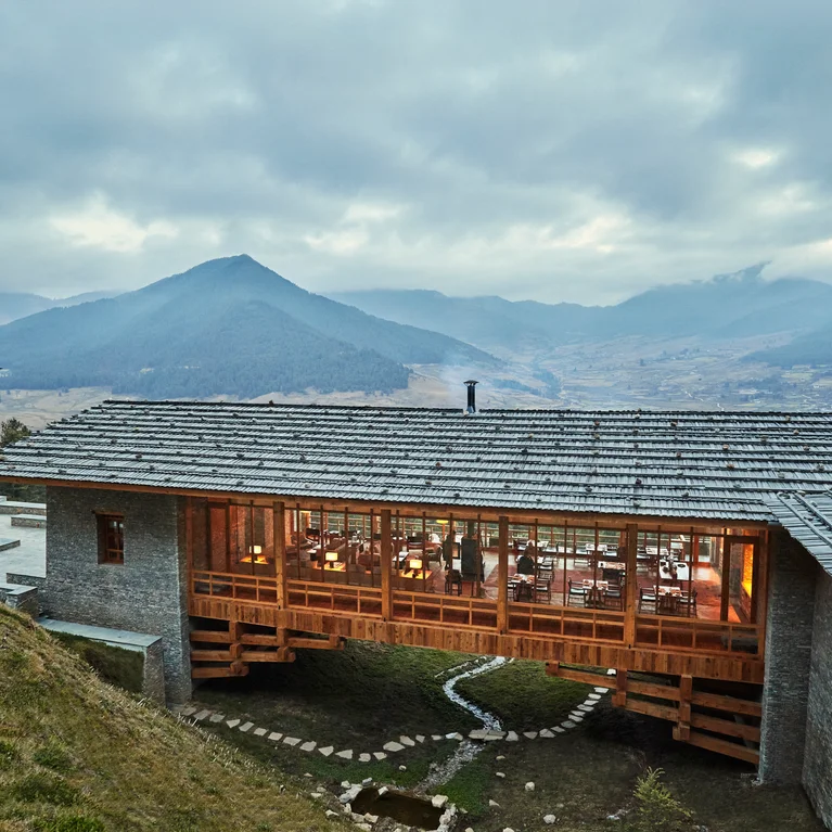 山坡上的小屋拥有宽大的窗户,在山景和云天的衬托下闪耀着温暖的光芒,突出了自然环境。.