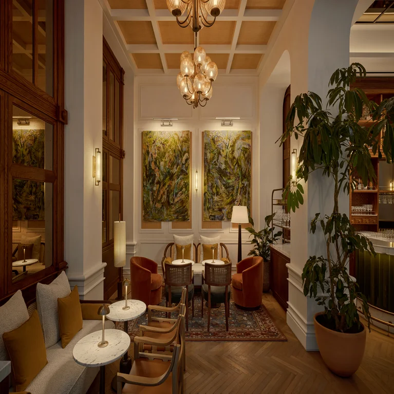 Inviting lounge featuring soft seating, round tables, contemporary lamps, leafy plants, abstract wall art and gentle lighting in a tranquil space focused on comfort and wellbeing.