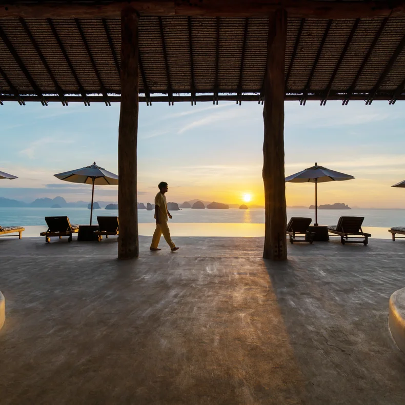 ラウンジチェアと傘に囲まれた静かなパティオからは、穏やかな海と夕暮れ時の遠くの島々が見渡せ、シックスセンシズが重視する静寂と心のこもったデザインが反映されている。.