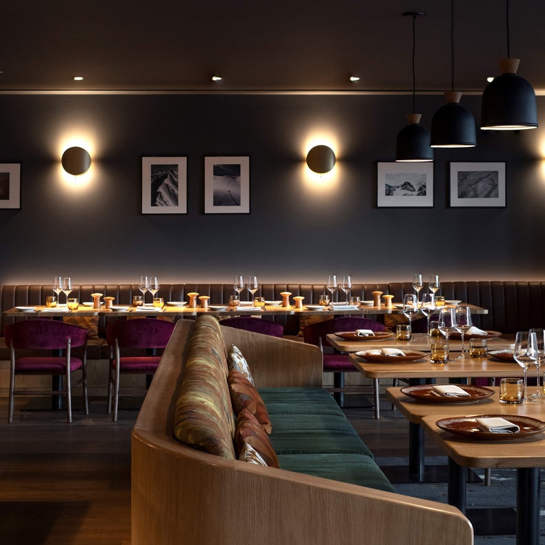 Le restaurant propose des tables en bois durable, des cabines douces, des éclairages suspendus et des œuvres d'art sélectionnées sur des murs aux tons profonds. Les tables sont dressées avec des verres et du linge de maison réutilisables.