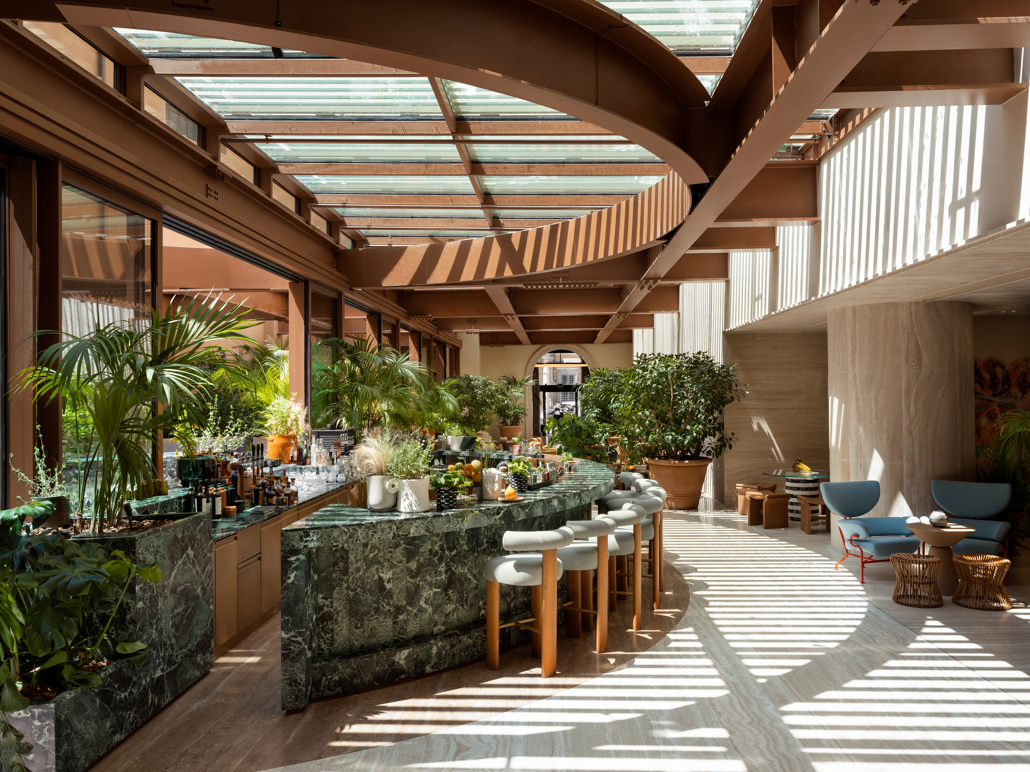 The green marble bar and lounge area at Six Senses Rome, filled with plants and natural light.