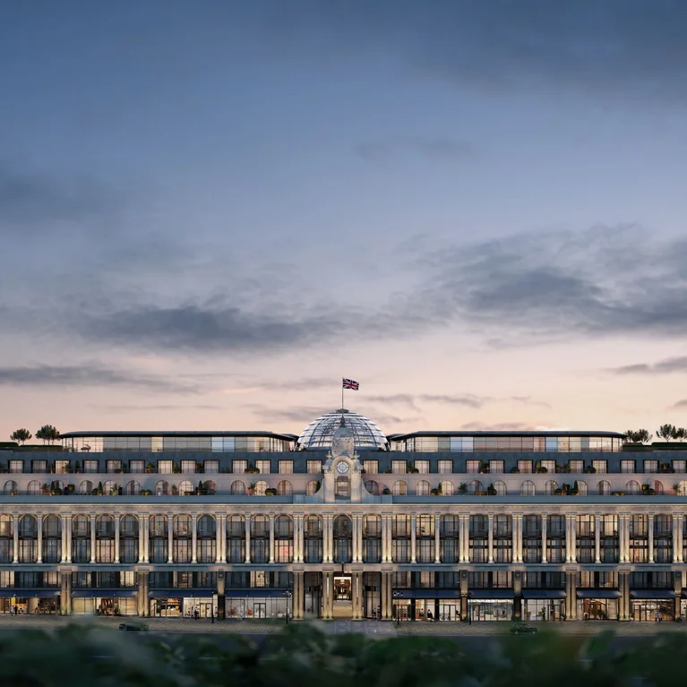 这座文物建筑有一个玻璃穹顶、四个角炮塔和屋顶上的一面旗帜,傍晚时分在阴云密布的天空下灯光柔和。.