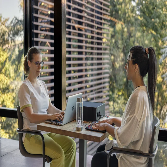 A guest enjoys a mindful technology experience as wellness sensors are gently placed, with natural greenery providing a calming backdrop through the window.
