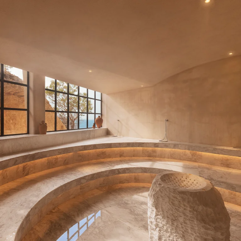 The hammam, a vaulted plaster chamber with a curved bench running round a shallow circular pool and a carved stone block at its centre, daylight entering through a steel-framed window.