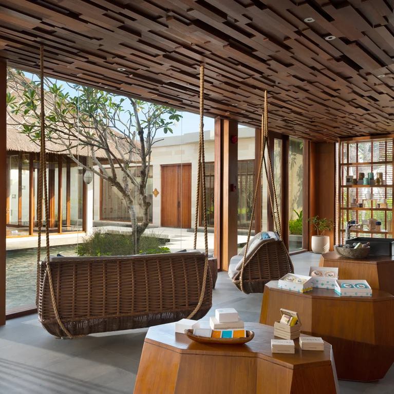 休息室设有木质秋千和矮桌,大窗户环绕着宁静的庭院、一个小泳池和一棵树。空间开阔,充满柔和的自然光。.