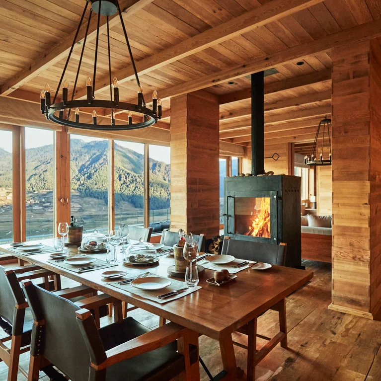 木质用餐区摆放着餐桌,宽大的落地窗将山景尽收眼底,毗邻的休息室还设有壁炉。无障碍布局和天然材料贯穿始终。.