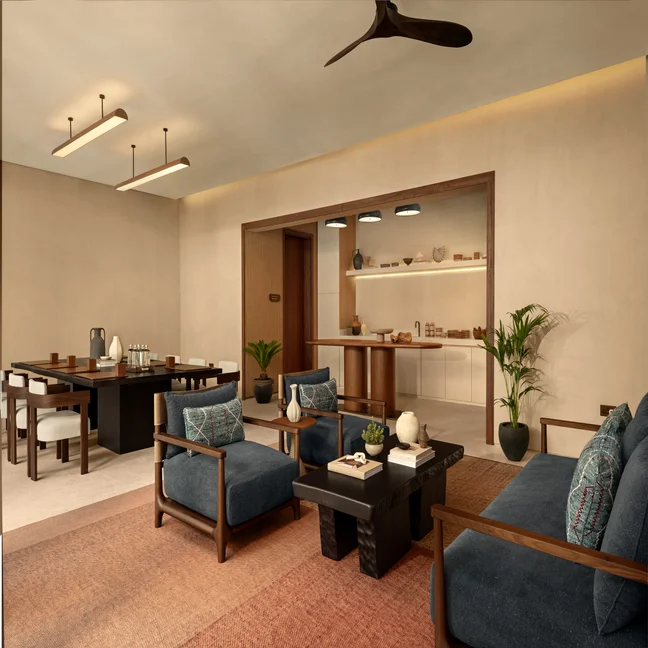 Living and dining space featuring natural wood furniture, blue cushions, indoor greenery, soft lighting, open shelves, and curated decorative accents.