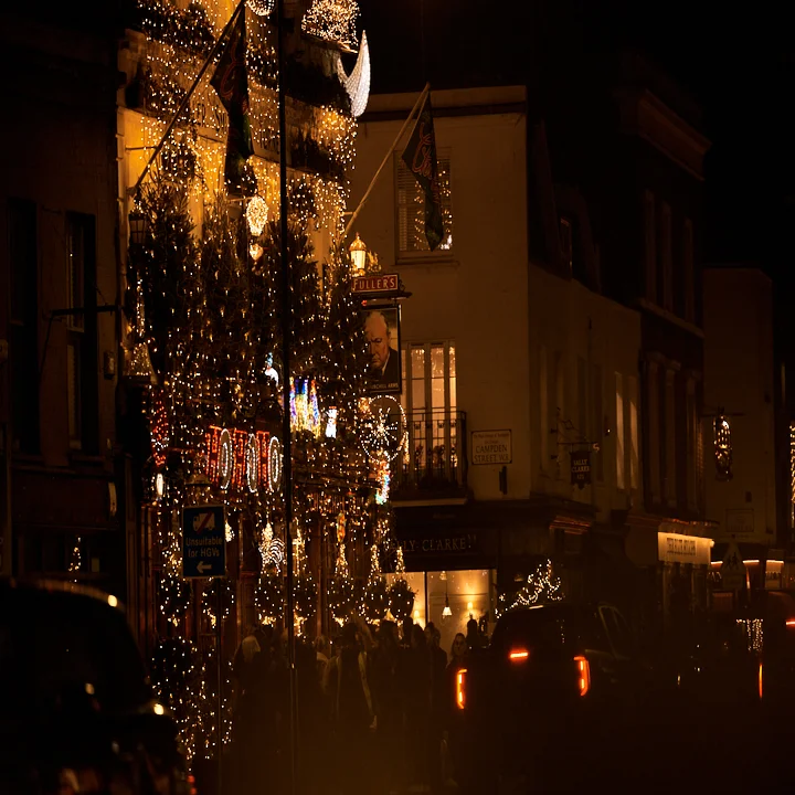 The Churchill Arms pub at night, adorned with numerous illuminated Christmas trees and festive lighting.