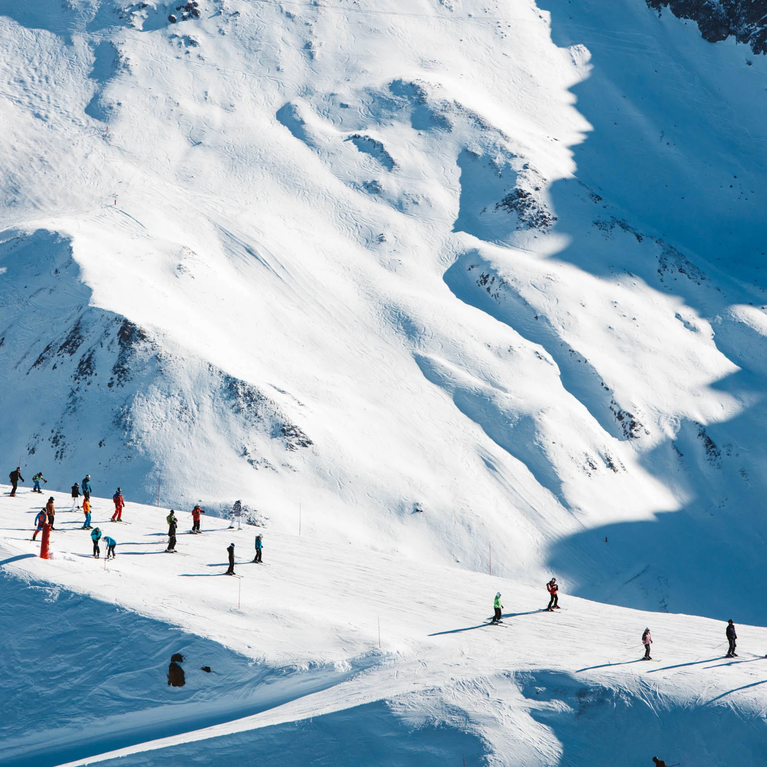 游客可以在晴空万里的雪坡上滑雪,周围是宁静的阿尔卑斯山峰和令人叹为观止的美景。.