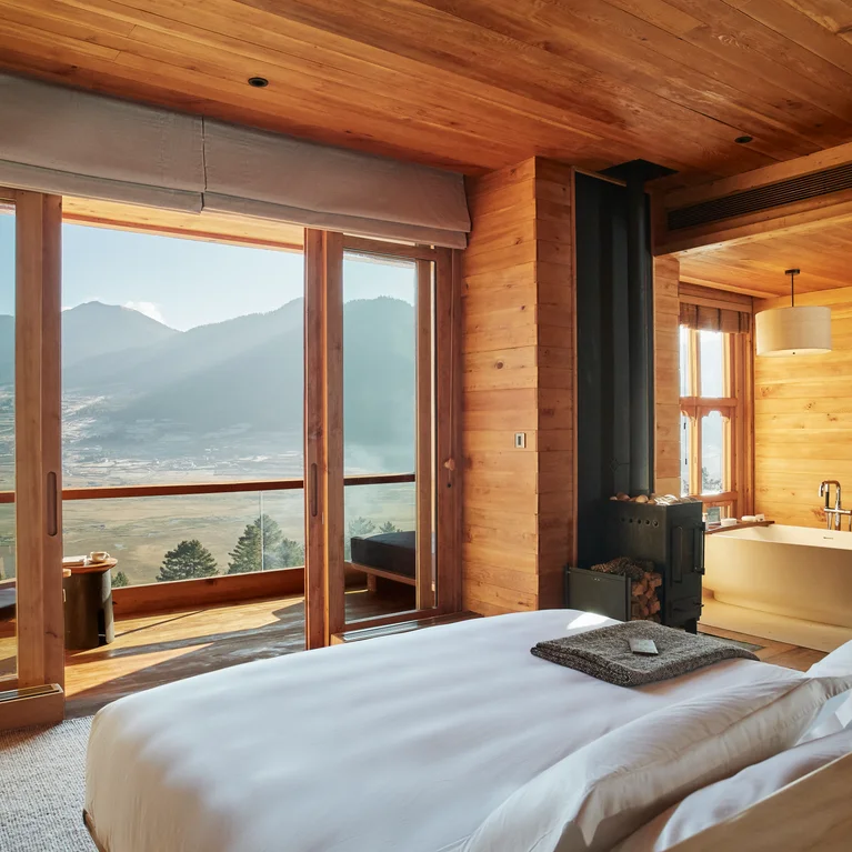 木板卧室配有一张大床、一个独立浴缸和通往阳台的滑动玻璃门,阳台上可欣赏到山峦和山谷美景。.