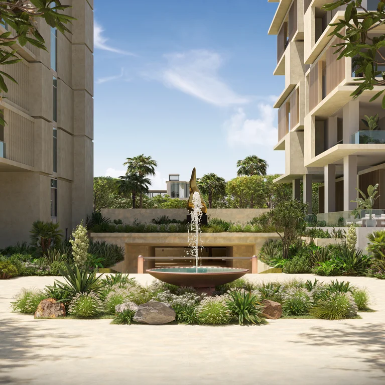 带阳台的低层住宅环绕着一个为健康而设计的庭院,庭院内有舒缓的喷泉、本地植被以及晴朗天空下的婆娑树影。.