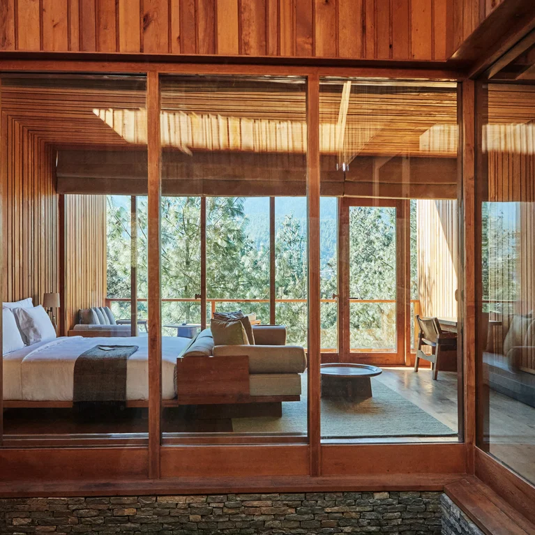 卧室配有木质装饰、大玻璃窗、床和沙发,布置舒适。自然光线充足,周围绿树成荫,环境宁静舒适。.