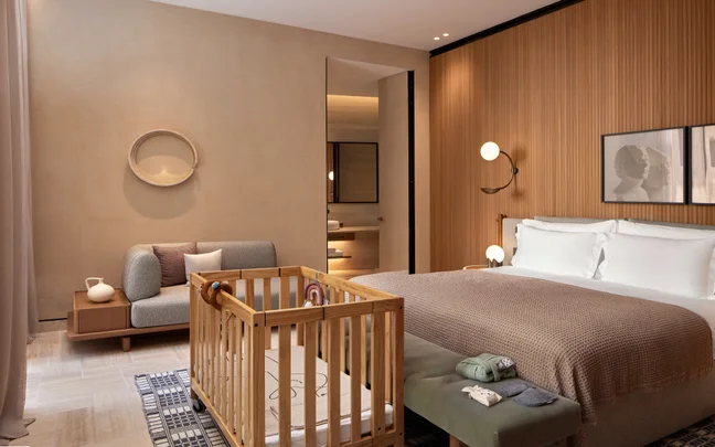 Guestroom features a king bed, crib, and sofa. Soft lighting, natural materials, and understated furnishings offer comfort. Accessible space thoughtfully designed for families.