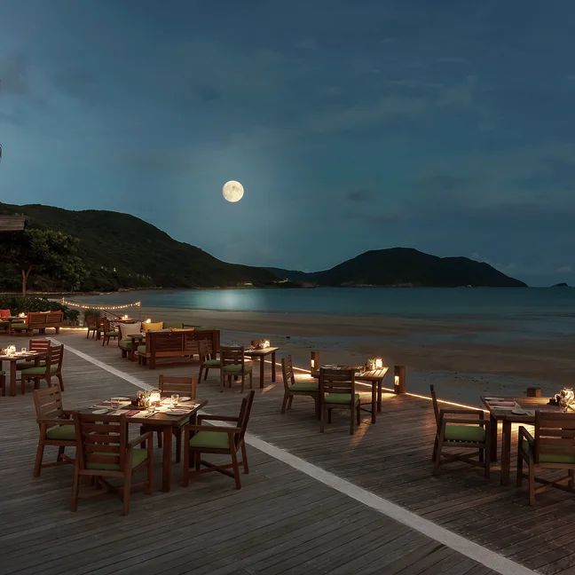 تم تأثيث منطقة تناول الطعام المطلة على الشاطئ بطاولات وكراسي خشبية مضاءة بنور القمر بهدوء، وتطل على المياه الهادئة والجبال البعيدة......