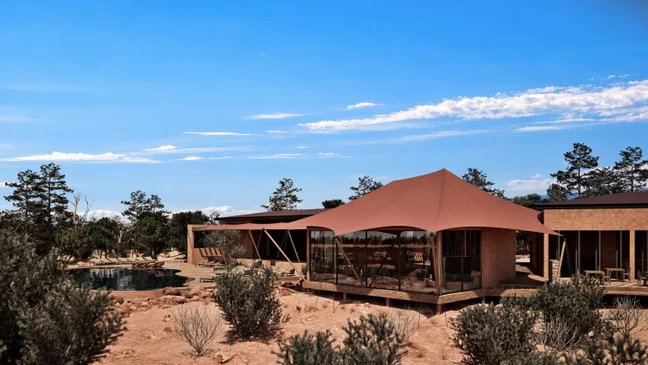Sustainable architecture with expansive windows and a neutral canopy set in a desert, encircled by native vegetation and a small pool under clear skies.