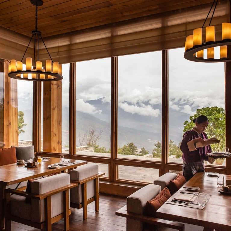 在一个现代风格的餐厅里,您可以通过大窗户俯瞰群山和云朵。柔和的灯光和木质装饰营造出宁静舒适的氛围。.