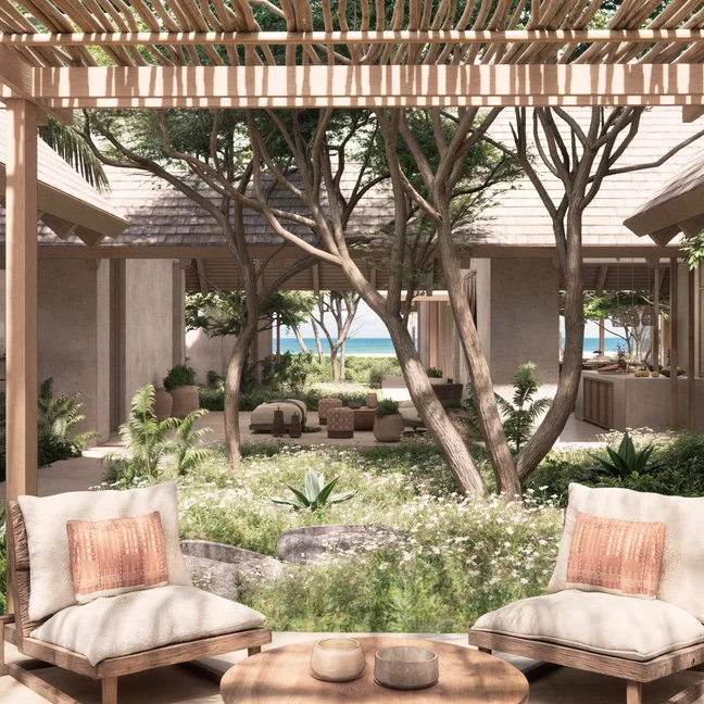 Lounge area featuring cushioned seating under a wooden pergola, surrounded by greenery and overlooking a courtyard with trees and pathway to the shore.