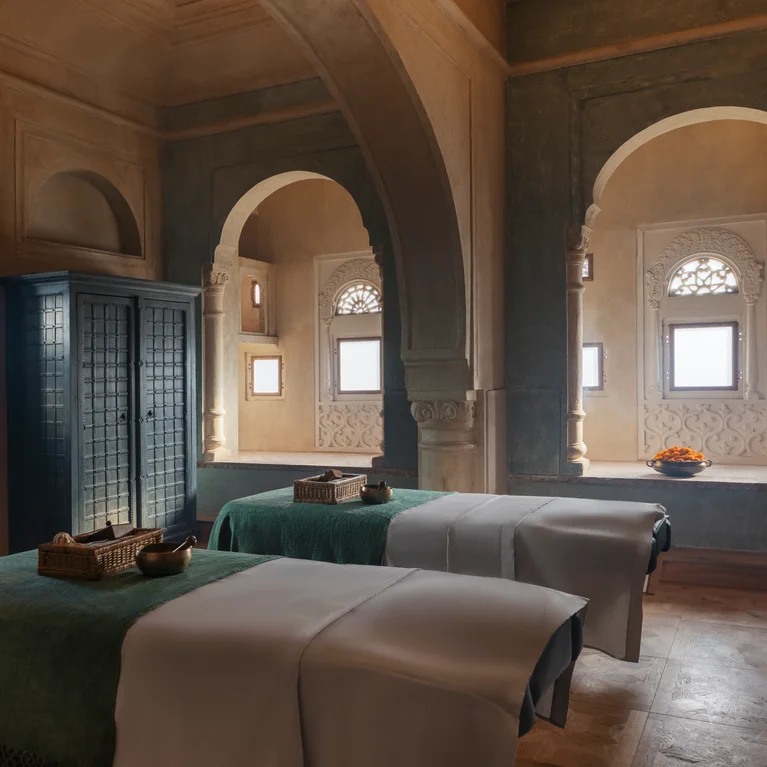 水疗套房内有两张按摩桌、弧形门洞、精致的窗户、柔和的灯光和精心摆放在每张桌子上的编织篮。.