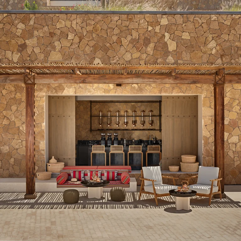 Sustainable pergola shades a lounge with soft seating, natural materials, and a discreet bar, blending indoor comfort with mindful outdoor design.