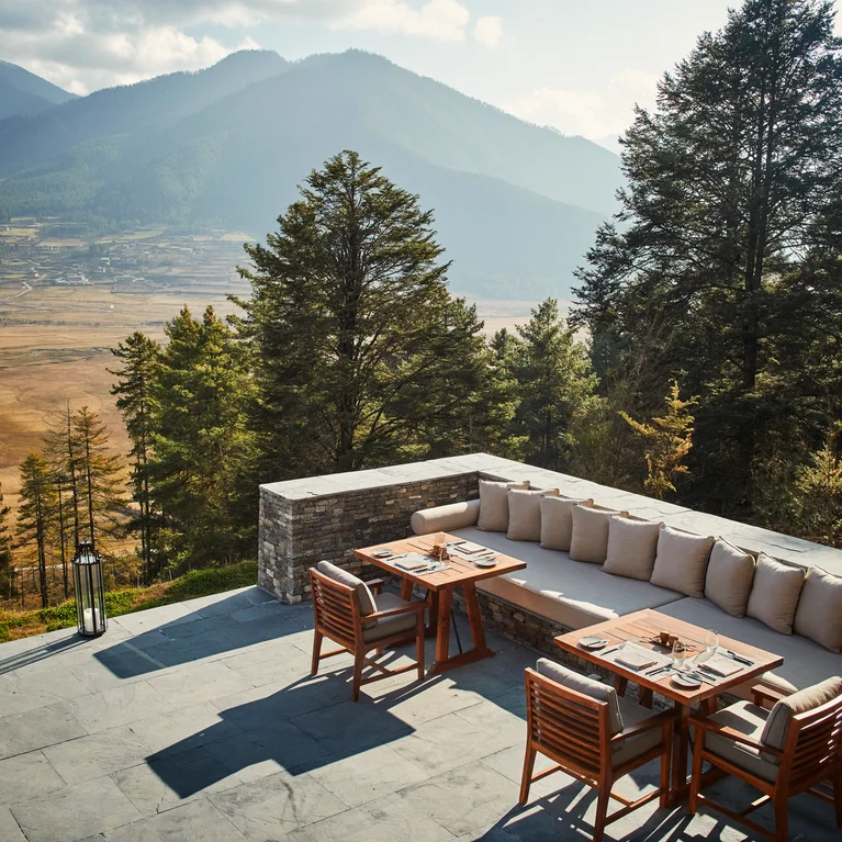 露台上摆放着舒适的座椅和木桌,在云雾缭绕的天空下,可以欣赏到绿色山谷、树梢和山脉的美景。.