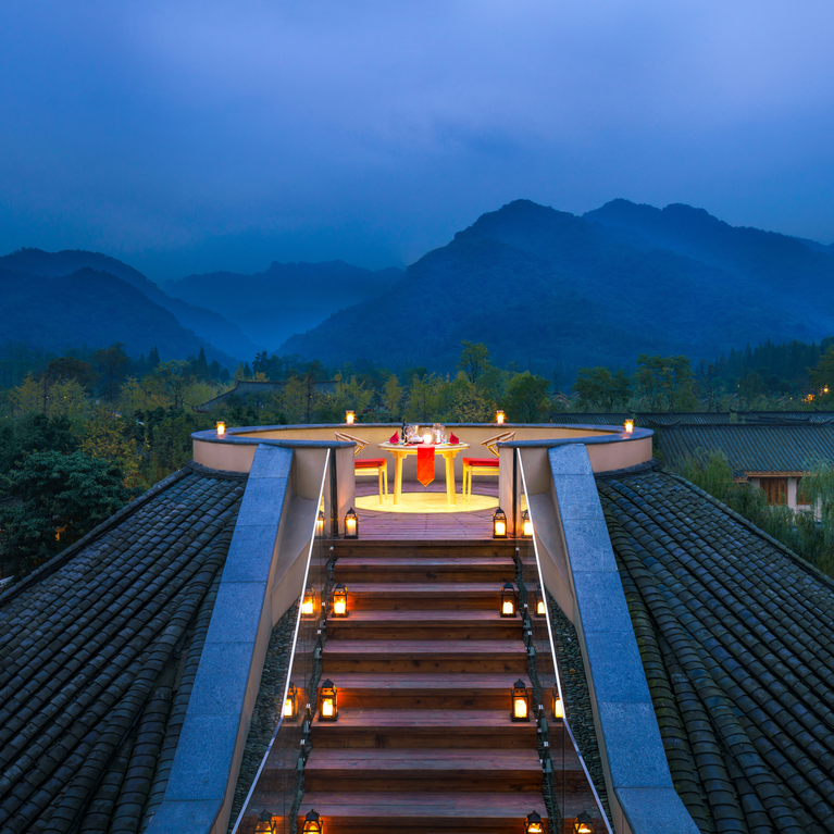 On the softly lit rooftop staircase you will find a dining table for two overlooking the tree-lined slopes and mountains in the shimmering light of the evening....